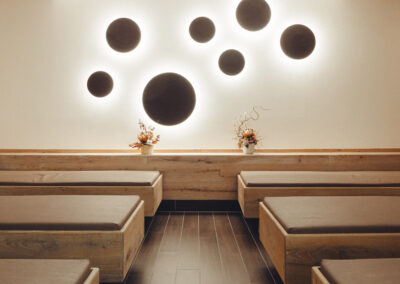 Moderner Ruheraum mit gepolsterten Liegen, Wandgestaltung mit großen, runden Lichtöffnungen – sanft ausgeleuchtet für Ruhephasen.