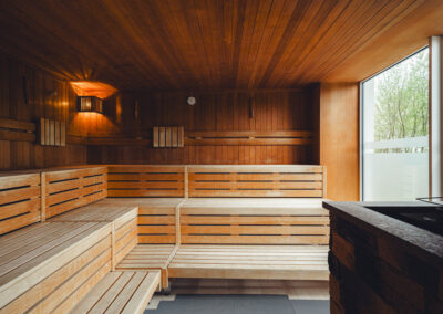 Klassische finnische Sauna aus hellem Holz mit drei Sitzebenen, niedriger Bankhöhe und integriertem Saunaofen – Darstellung traditioneller Saunakultur.