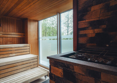 Klassische finnische Sauna aus hellem Holz mit drei Sitzebenen, niedriger Bankhöhe und integriertem Saunaofen – Darstellung traditioneller Saunakultur.