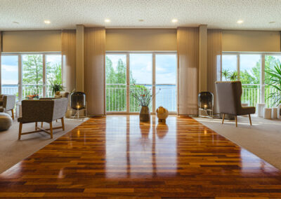 Großer Mehrzweckraum mit Parkettboden und bodentiefen Fenstern, symmetrische Deckenlampen, barrierefreier Zugang möglich.